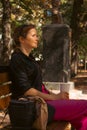 Girl with coffee cup sitting on the bench in park. Woman relaxing in autumn alley. Fall in downtown. Street lifestyle. Royalty Free Stock Photo