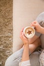 Girl with coffee mug sitting on the sofa indoors. Woman drinking a cup of coffee or tea sitting cozy at home. Relax