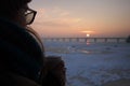 A girl with coffee paper cup in her hands is enjoying sunrise on bank of River Dnipro. Close-up photo.