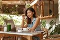 Girl At Coffee Shop. Asian Woman With Laptop Thinking And Going To Note Something In Planner Book Royalty Free Stock Photo