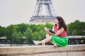 Girl with coffee to go reading a book near the Eiffel tower. Royalty Free Stock Photo