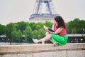 Girl with coffee to go reading a book near the Eiffel tower. Royalty Free Stock Photo