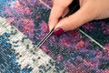 Girl collect diamond painting. Diamond embroidery with a tweezers. Acrylic rhinestones. Closeup, selective focus