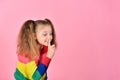 A girl in a colored sweater raised a finger to her lips and speaks, urging her to remain silent Royalty Free Stock Photo