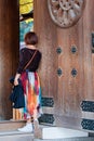 Girl in colorful skirt near the wooden doors of the temple, Tokyo, Japan. Vertical. Royalty Free Stock Photo