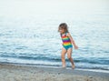 Girl in a colorful swimsuit runs out of the sea