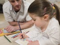 Girl Coloring Pictures With Father Looking At It Royalty Free Stock Photo