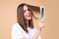 Girl combing hair. Beautiful young woman holding comb straightened hair. Attractive smiling woman portrait with comb. Royalty Free Stock Photo