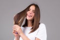 Girl combing hair. Beautiful young woman holding comb straightened hair. Attractive smiling woman portrait with comb. Royalty Free Stock Photo