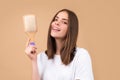 Girl combing hair. Beautiful young woman holding comb straightened hair.