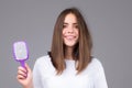 Girl combing hair. Beautiful young woman holding comb straightened hair. Royalty Free Stock Photo