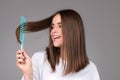 Girl combing hair. Beautiful young woman holding comb straightened hair. Royalty Free Stock Photo