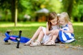 A girl comforting her sister after she fell while riding her scooter Royalty Free Stock Photo