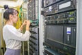 The girl commutes the wires of powerful Internet routers. A woman switches the cable in the server room. The system administrator