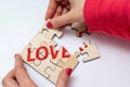 Girl connects disconnects wooden puzzles with the text Love. The concept of building or breaking love relationships. Top view