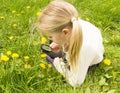 Girl considers dandelions flower through a magnifying glass Royalty Free Stock Photo