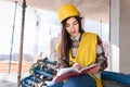 Girl in a construction helmet and vest writes in a notebook at a construction site Royalty Free Stock Photo