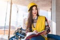 Girl in a construction helmet and vest writes in a notebook at a construction site Royalty Free Stock Photo