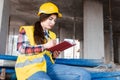 Girl in a construction helmet and vest writes in a notebook at a construction site Royalty Free Stock Photo