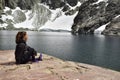 A girl contemplates the mountains and the glaciers that fall to a lake