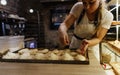 a girl cook in a cafe sprinkles coconut shavings on raw pies lying on a tray. open kitchen cooking