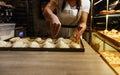 a girl cook in a cafe sprinkles coconut shavings on raw pies lying on a tray. open kitchen cooking