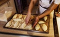 a girl cook in a cafe sprinkles coconut shavings on raw pies lying on a tray. open kitchen cooking. top view