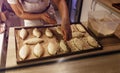 a girl cook in a cafe sprinkles coconut shavings on raw pies lying on a tray. open kitchen cooking. top view