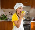 A girl in cook`s clothes holds an apple in her hand