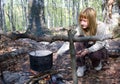 Girl cooking food on fire in camp Royalty Free Stock Photo