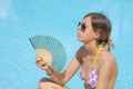 Girl cooling with the fan by the pool Royalty Free Stock Photo