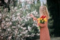 A girl in a coral dress with a bouquet of yellow and red tulips