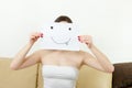 Girl cover her face with joyful teasing smile drawn on paper.