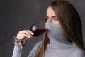 Girl with covered face drinking wine. Close up. Gray background