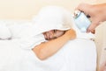 Girl covering head with pillow and being awakened by alarm clock Royalty Free Stock Photo