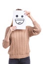 Girl covers the face with a white leaf with a cheerful smiley face on a white background