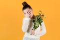 Girl covers her face in crying, she holds withered flowers in her hands