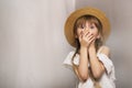 Girl covers her mouth with her hands, smoke indoors