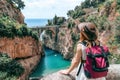 A girl in a cowboy hat with a backpack enjoys an incredibly beautiful view of a stone bridge over the gorge Fiordo di Furore. Royalty Free Stock Photo