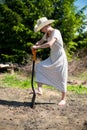 Girl in a cowboy hat with shovel digging hole