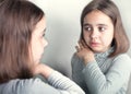 The girl cries, looking at her reflection in the mirror. Royalty Free Stock Photo