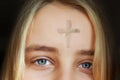 Girl with cross made from ash on forehead. Ash wednesday concept. Royalty Free Stock Photo