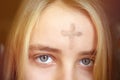 Girl with cross made from ash on forehead. Ash wednesday concept. Royalty Free Stock Photo