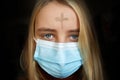 Girl with cross made from ash on forehead with face mask. Ash wednesday concept. Royalty Free Stock Photo