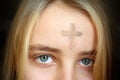 Girl with cross made from ash on forehead. Ash wednesday concept. Royalty Free Stock Photo