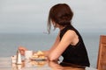 A girl in a cruise liner restaurant is eating a cake and looking out into the ocean closeup