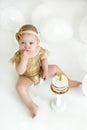 Girl crushes eating first cake on birthday on white background with balloons Royalty Free Stock Photo