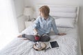 Girl with cup in her hand, kettle and tablet on a white bed looking in window Royalty Free Stock Photo