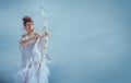 Girl cupid with wings aiming with bow and arrow on a sky background. Valentines day concept. Angel teen in heaven Royalty Free Stock Photo