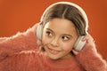 Girl cute little child wear headphones listen music. Kid listen music orange background. Recommended music based on Royalty Free Stock Photo